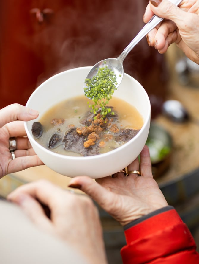 Beuschelsuppe mit Schwarzbrot, Grammeln und Schnittlauch.