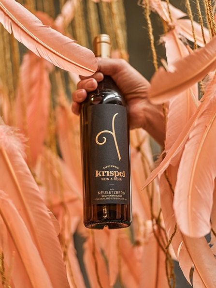 Hand hält eine Flasche Neusetzberg Krispel Wein.